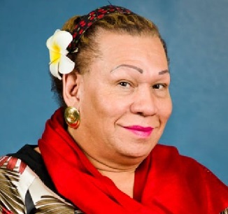 A woman smiling at the camera with a white flower in her hair